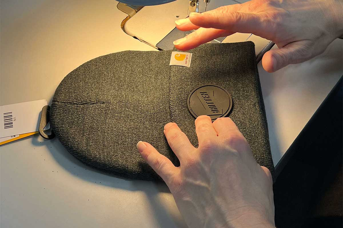 PVC patch being sewn to a carhartt beanie