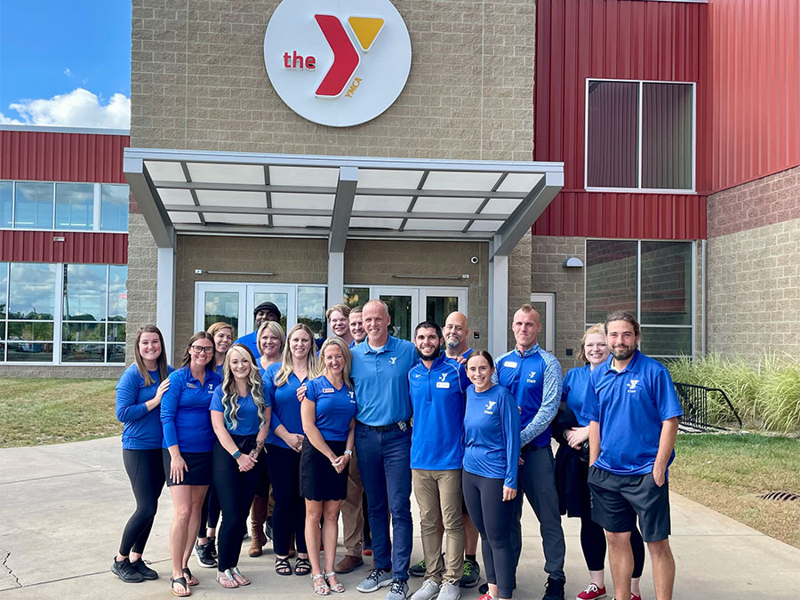 Staff members in matching shirts standing in front of the YMCA building